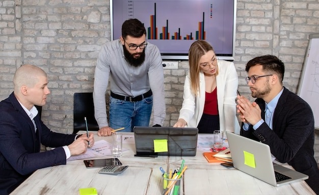 Business partners discussing project ideas with charts and laptops in office