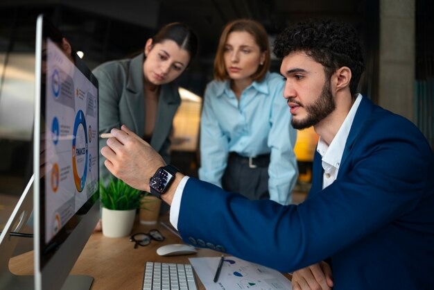 Team analyzing finance data on a computer screen during office meeting