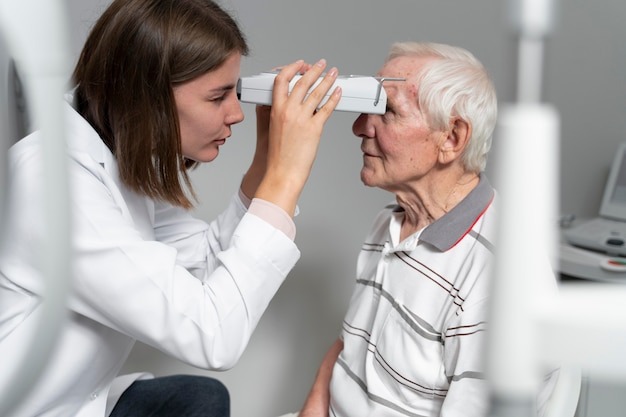 From Blur to Clear with Today’s Eye Care Advances 3 Eye doctor examining an elderly man’s vision using a handheld ophthalmic device in a clinic setting.